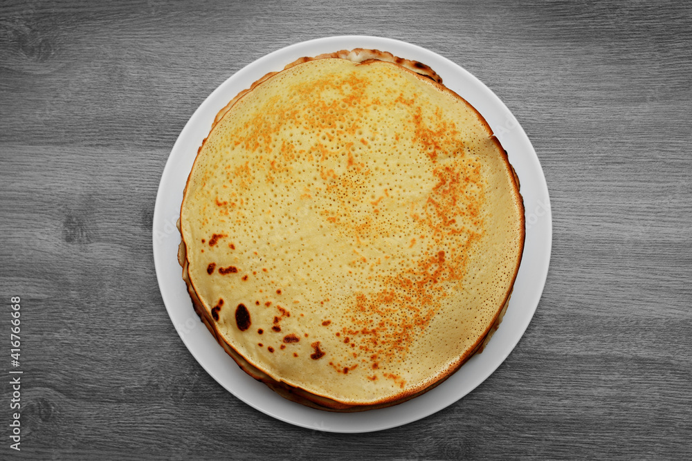 Pancakes on a white plate top view on a table with a wooden texture Pancakes on a white plate top view on a table with a wooden texture