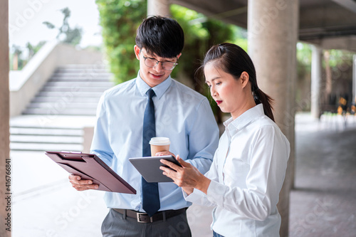 Young business woman holding tablet and looking to this presentation investment to young business man