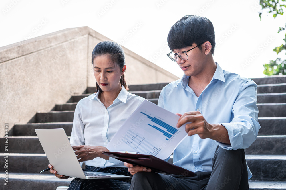 Young business man holding document paper and checking financial report on laptop with businesswoman Young business man holding document paper and checking financial report on laptop with businesswoman