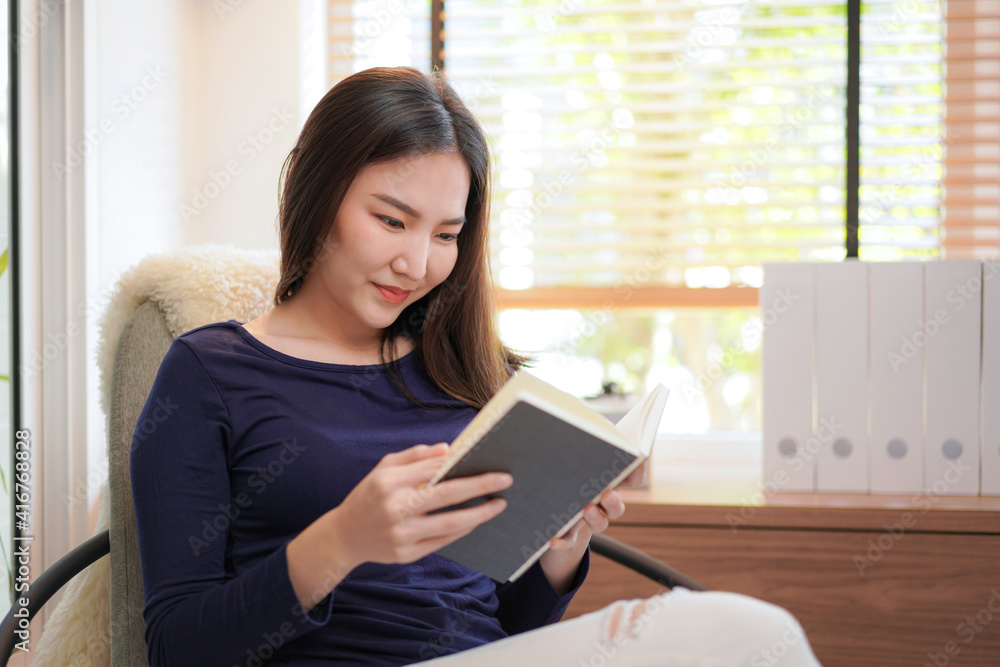 Close up of young asian woman sitting to relaxing on comfortable armchair and reading book while rest Close up of young asian woman sitting to relaxing on comfortable armchair and reading book while rest