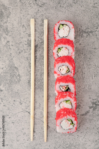 Sushi rolls with red caviar and chopsticks on marble background