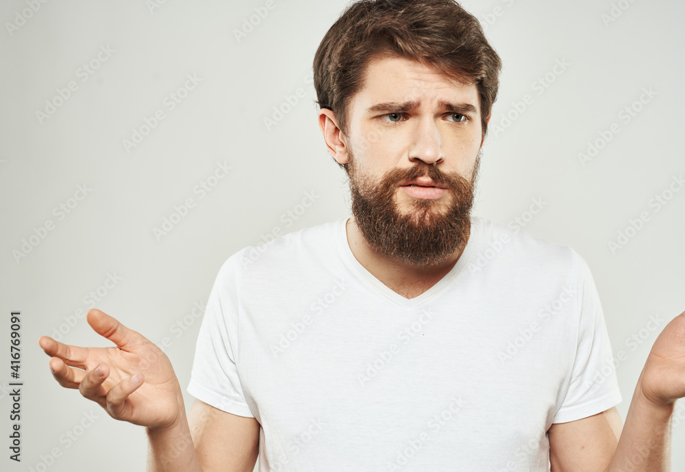 The man looks ahead in a puzzled way on a light background of emotions cropped view The man looks ahead in a puzzled way on a light background of emotions cropped view