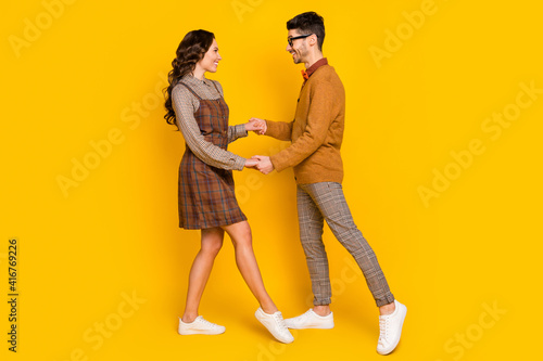 Full size profile side photo of attractive man hand woman dance hold hands isolated on yellow color background