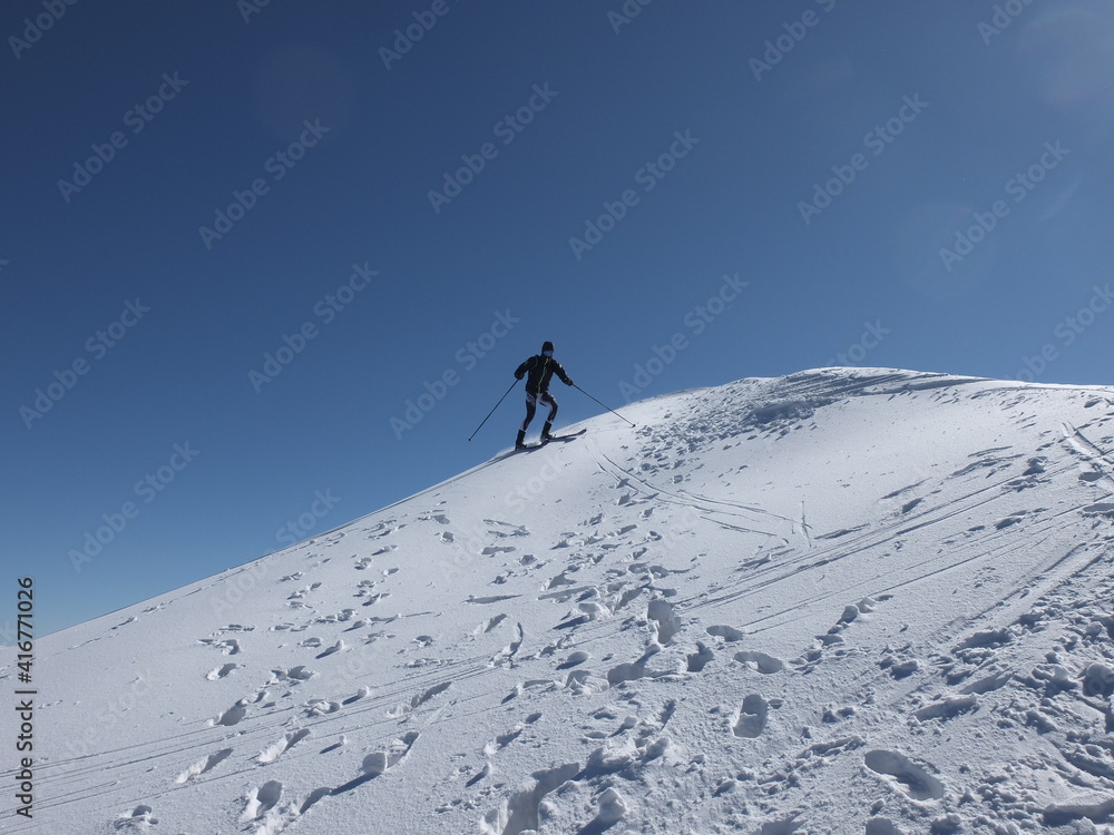 silhouette de skieur de rando alpiniste dans la neige et le vent des cristaux de glace