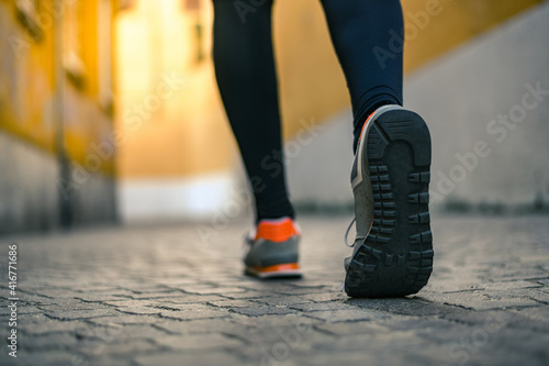 Close up of male feet walking during workout. Legs of man run in the city and jogging alone. Crocodile view of a runner doing sport activity in a deserted town. Closeup of running shoes stepping.