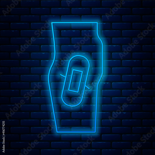 Glowing neon line Plaster on leg icon isolated on brick wall background. Vector.