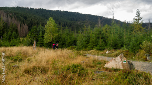 Tourists couple on pathway in Tatra mountains. Green tourist trail mark on a stone.