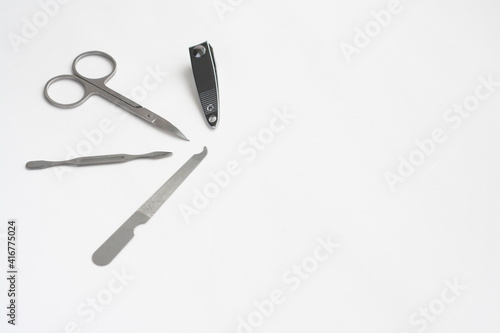 Metal manicure set, tweezers, scissors, file and spatula isolated on white background, copy space