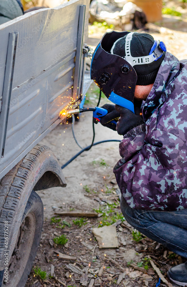welder works at home in a protective mask without gloves welder works at home in a protective mask without gloves