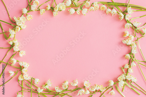 Flowers frame flat lay on pink paper. Stylish floral greeting card, space for text. Hello spring
