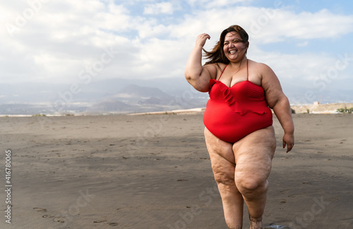 Happy plus size woman having fun walking on the beach - Curvy confident people lifestyle concept