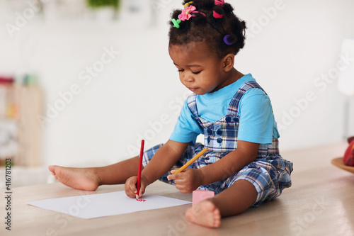 cute toddler baby girl drawing with pencils using both hands photo