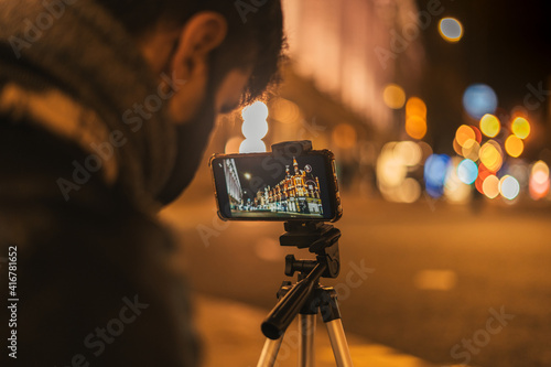Young man taking a picture in the street at night time. photo