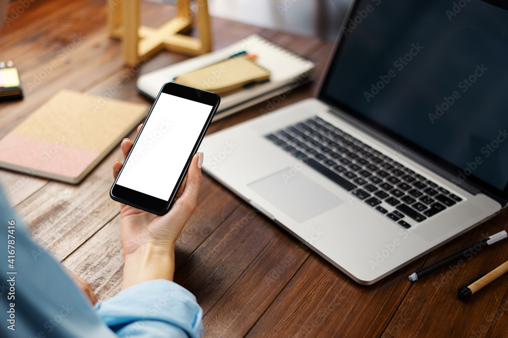 Mockup image of a woman using smartphone with blank screen on wooden table. Mockup image of a woman using smartphone with blank screen on wooden table.