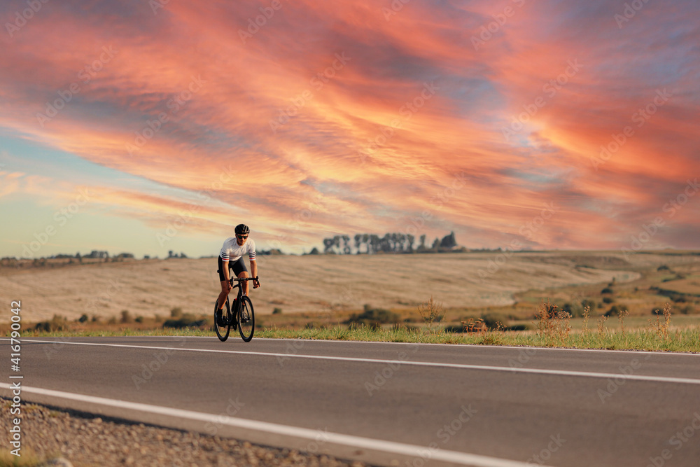 Obraz premium Active young man cycling on road during sunny day