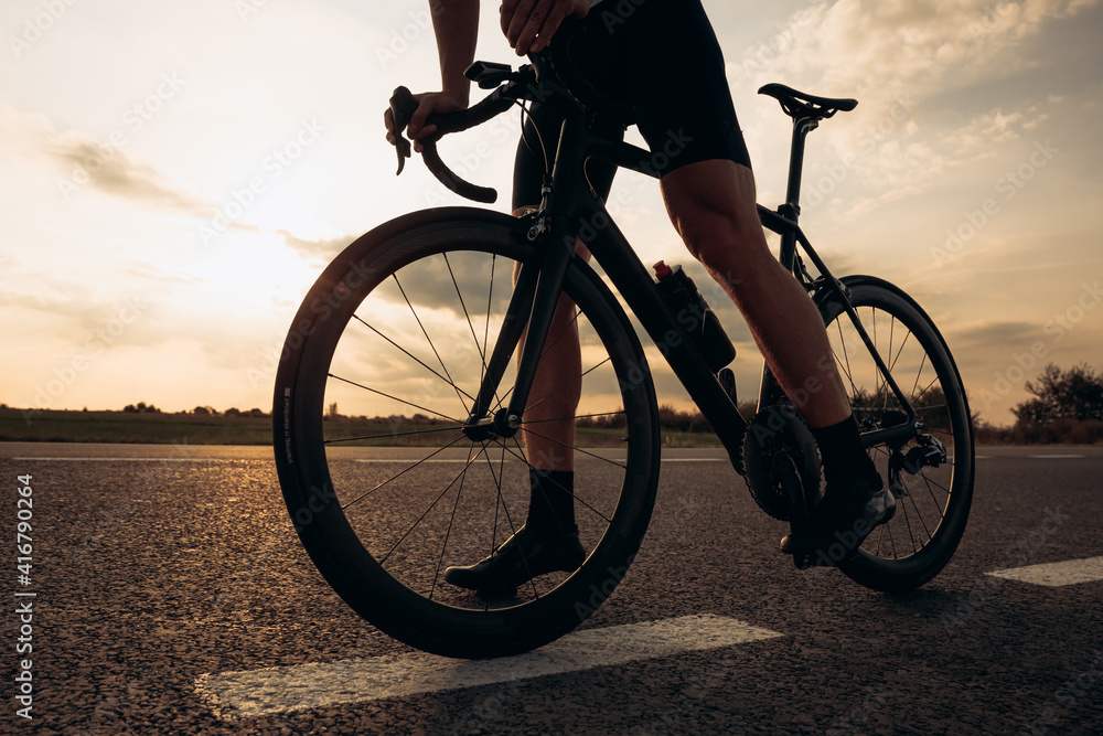 Fototapeta premium Close up of sporty young man standing on road with bike