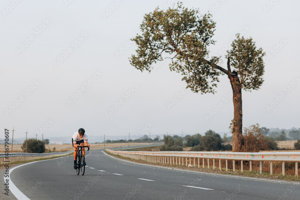 Muscular man riding bike with high speed on road