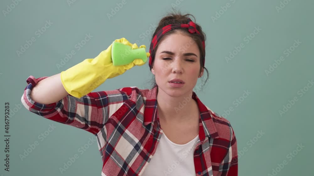 A focused woman is cleaning the screen standing isolated over a green background in the studio A focused woman is cleaning the screen standing isolated over a green background in the studio