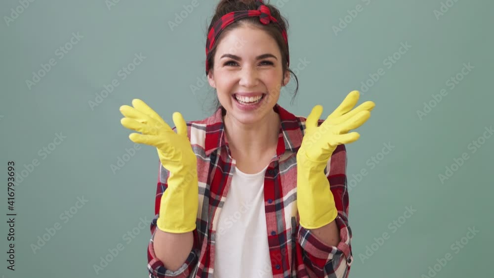 A happy cleaner woman is rejoicing while clapping her hands standing isolated over a green background in the studio A happy cleaner woman is rejoicing while clapping her hands standing isolated over a green background in the studio