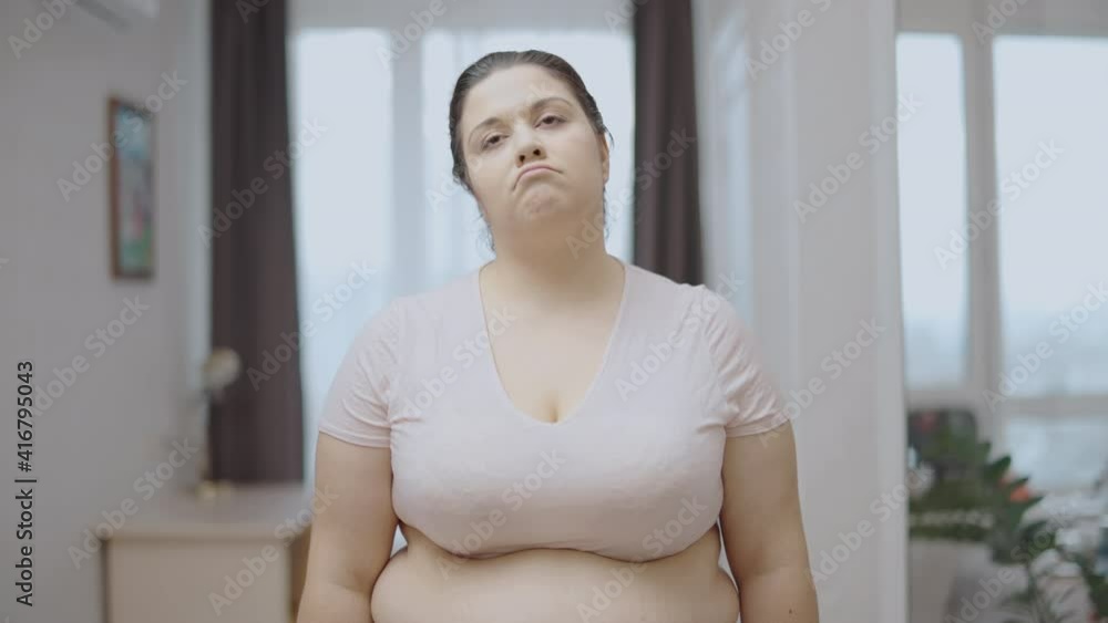 Upset oversize woman looking at measuring tape, fat around waistline, weightloss Upset oversize woman looking at measuring tape, fat around waistline, weightloss