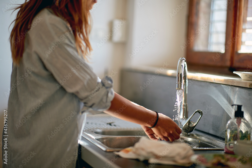 A young girl washing dishes in the kitchen. Housework, kitchen, home