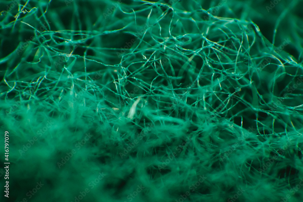 Macro photography of sponge fibers for washing dishes. The texture is green.