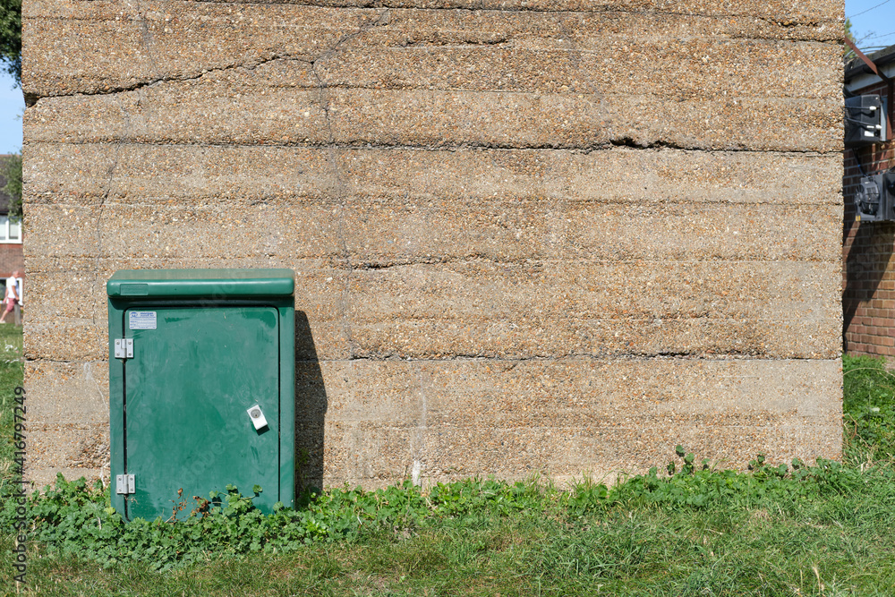 Obraz premium Old concrete building with utilities cabinet in Dovercourt Essex. Weathered old concrete building, green utilities cabinet on the edge of a open recreation area in Dovercourt near Harwich in Essex.
