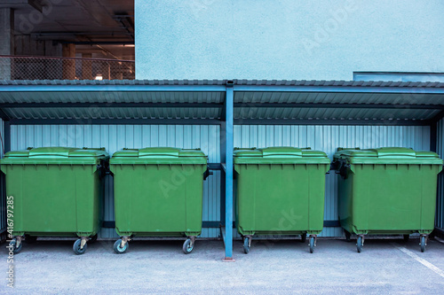 garbage green containers, litter boxes stand under a canopy without signs and garbage
