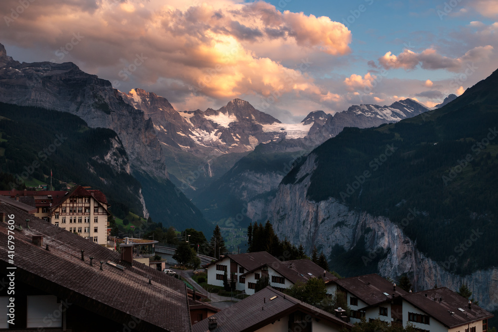 Wengen and the Lauterbrunnen valley at sunset in summer with warm orange clouds providing a dramatic sky over the Bernese Alps. Bernese Oberland, Switzerland