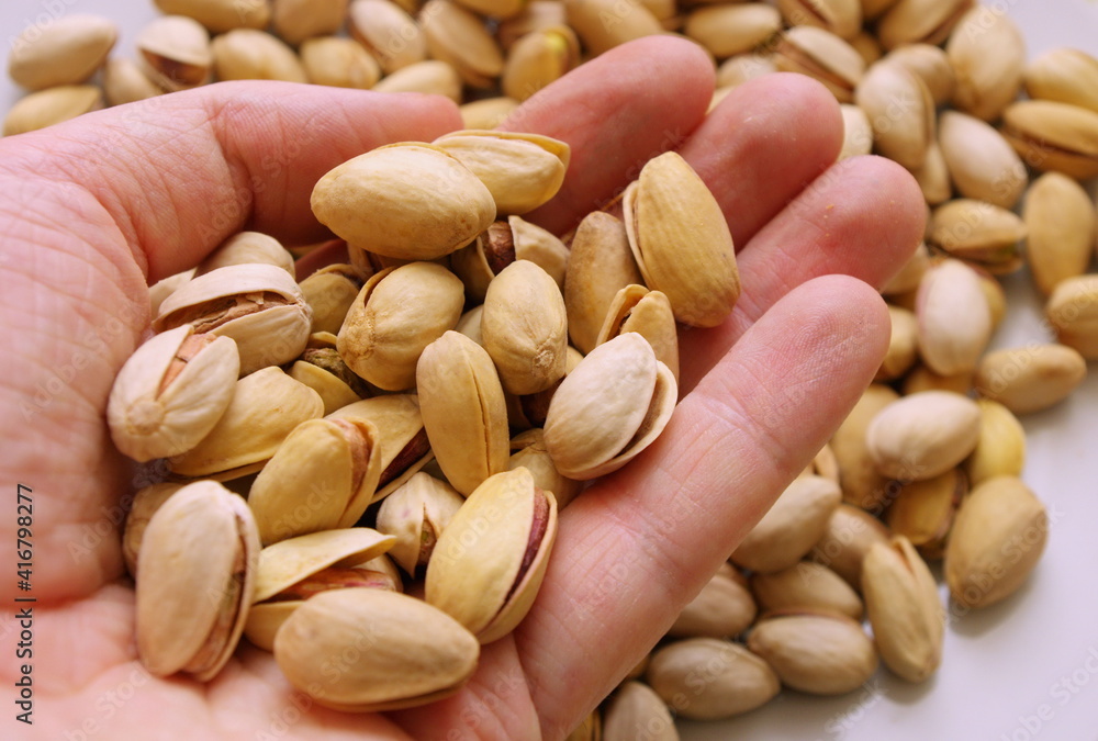 Hand holding pistachio nuts. Healthy food and snacks. Nuts, pistachios. Background of nuts. Top view or flat lay. Tasty pistachios as background. Walnut, pistachios, almonds, hazelnuts and cashews. Hand holding pistachio nuts. Healthy food and snacks. Nuts, pistachios. Background of nuts. Top view or flat lay. Tasty pistachios as background. Walnut, pistachios, almonds, hazelnuts and cashews.