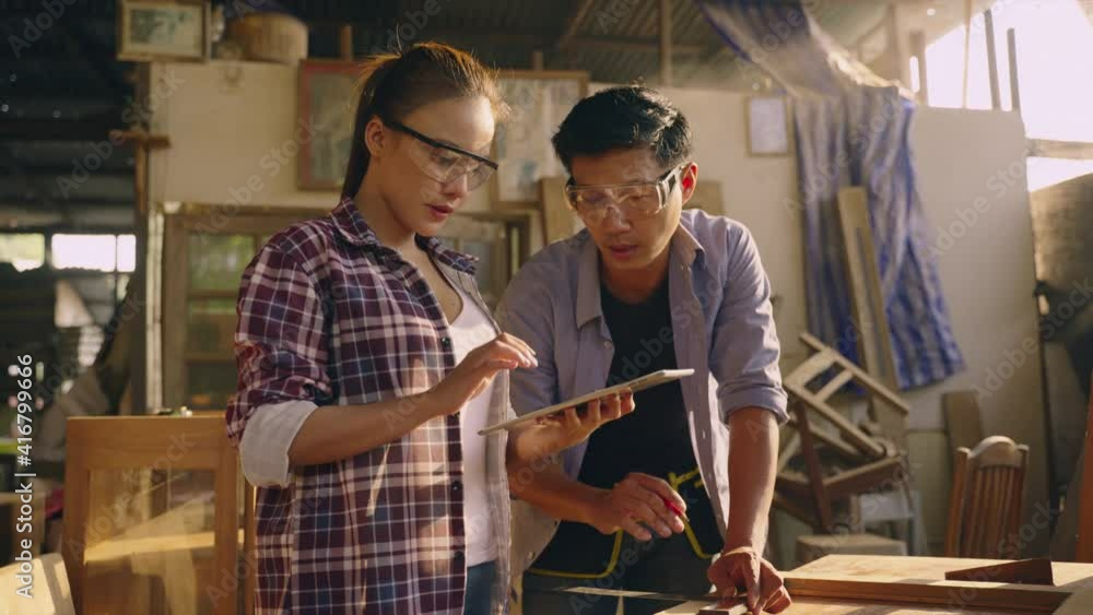 Asian carpenter or craftsman teach woman worker for wood working in workplace area and they look happy to discuss together. team are check quality the wood specification in product. Asian carpenter or craftsman teach woman worker for wood working in workplace area and they look happy to discuss together. team are check quality the wood specification in product.