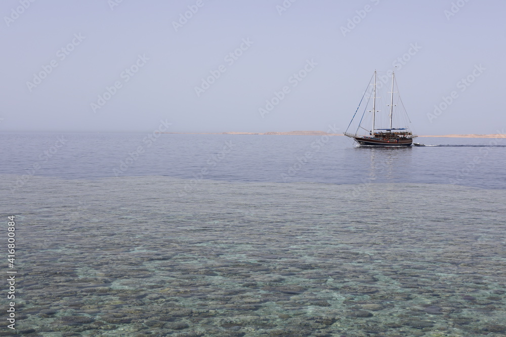 sail boat on the sea. Scenic seascape with swimming yacht near the coral reef in the Red Sea. Landscape of Egyptian coral coast and transparent clean water. 