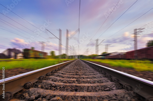 Railroad in motion with motion blur effect at sunset with beautiful sky. Railway transportation.