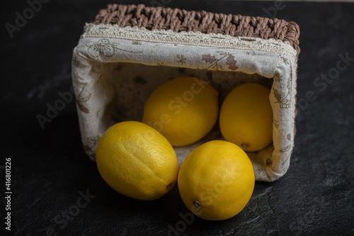 Fototapeta Naklejka Na Ścianę i Meble -  Basket full with fresh ripe lemons on black background