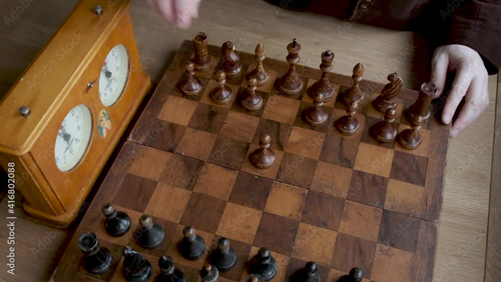 Close up chess game, male hand makes first move with wooden pawn, vintage wooden chess, selective focus Close up chess game, male hand makes first move with wooden pawn, vintage wooden chess, selective focus