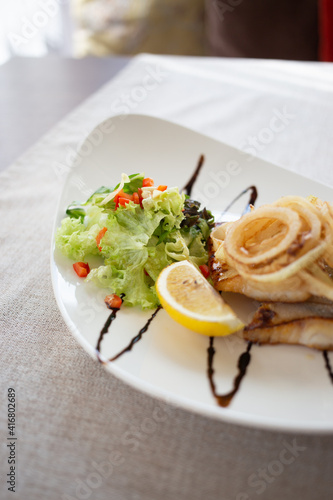 Fish under an onion pillow with salad