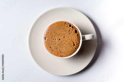 Flat lay black coffee with foam in a white cup isolated on white background.
