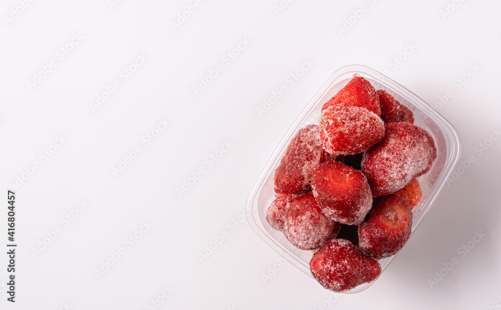 Frozen strawberry in plastic box isolated on white background. Frozen strawberry in plastic box isolated on white background.