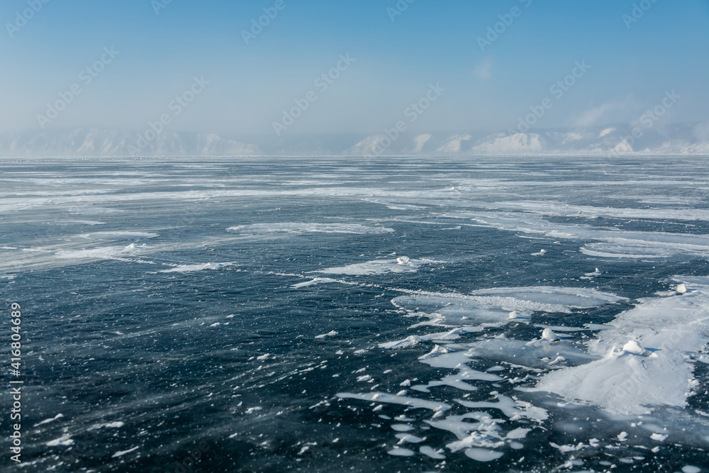 Frozen Baikal lake and wind. Clear ice and snow