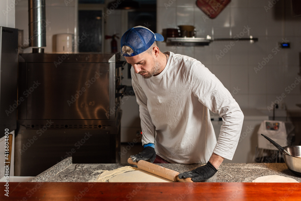 pizza boy kneads pizza dough in a pizzeria restaurant kitchen pizza boy kneads pizza dough in a pizzeria restaurant kitchen