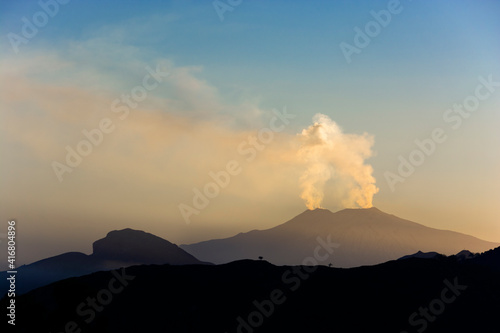 View of the silhouette of the Etna volcano erupting from the Peloritani mountains in Sicily Italy