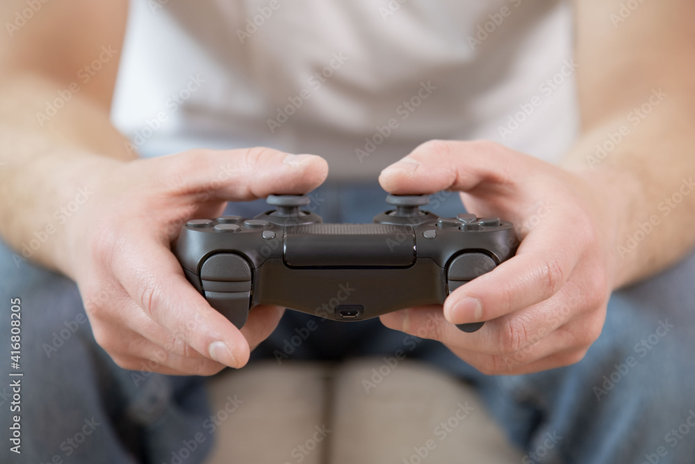 Playing games concept. Man holding  joystick and play video games, close up.