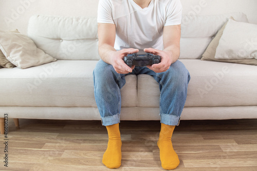 hipster man holding joystick while playing computer games. Computer games concept. Guy sitting on comfort sofa and playing video games.