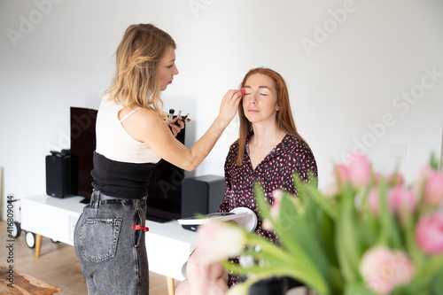 A stylist, makeup artist, cosmetician is doing makeup.  Applying cosmetic on the face. Natural makeup. Two women in beauty parlor