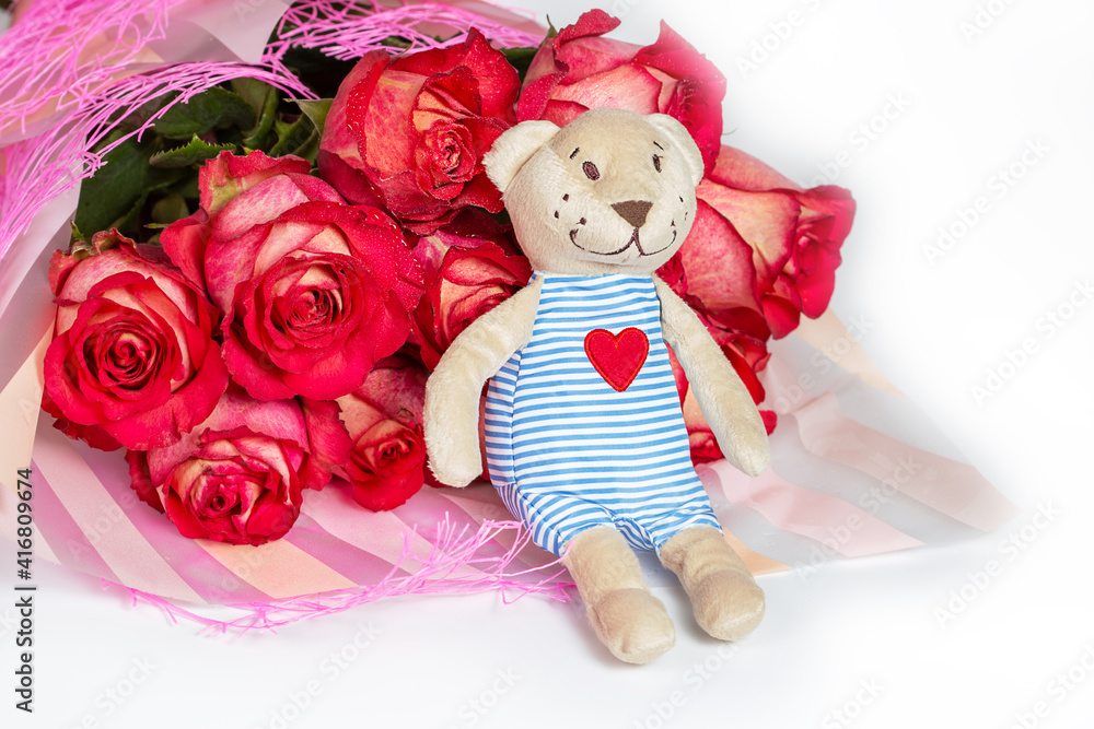 Fototapeta premium A bouquet of red roses in a gift paper package and a soft toy bear