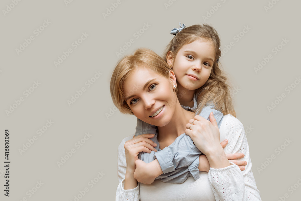 the concept of maternal love and care. mom and little daughter hug on gray background copy space happy family, parenthood the concept of maternal love and care. mom and little daughter hug on gray background copy space happy family, parenthood
