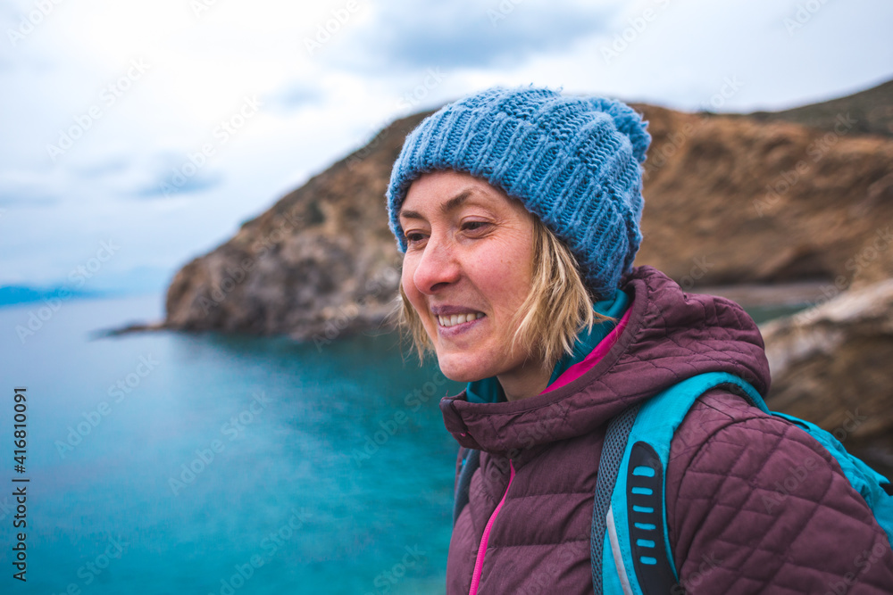 Portrait of a smiling girl in a knitted hat while walking along the sea coast Portrait of a smiling girl in a knitted hat while walking along the sea coast