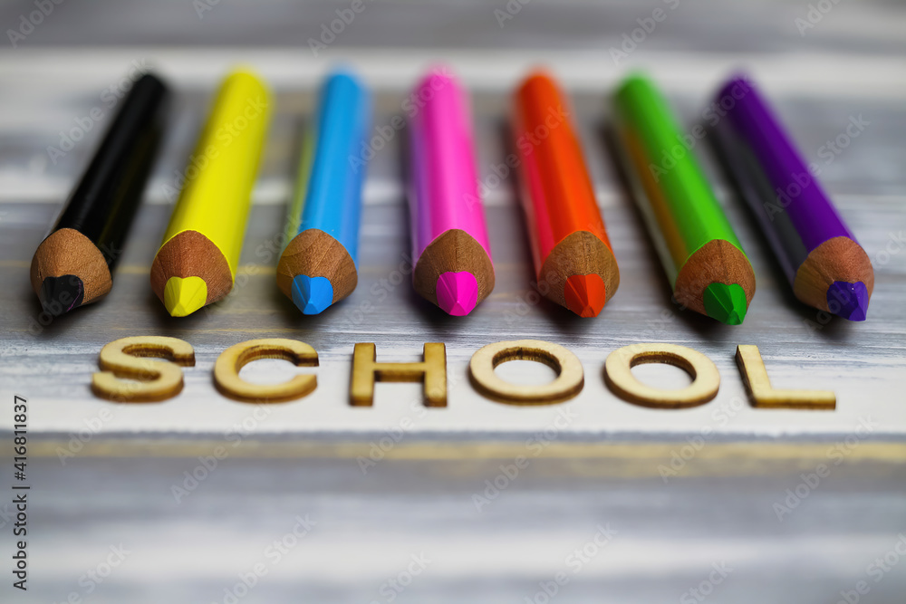 Closeup of row multi colored crayons on wood table with word school Closeup of row multi colored crayons on wood table with word school