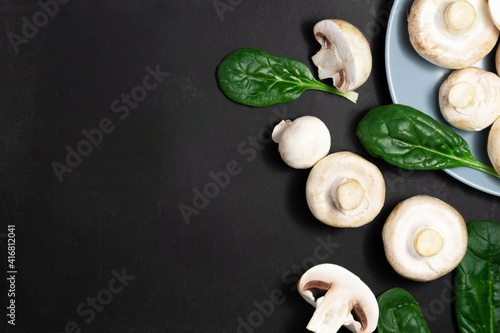 Raw mushrooms champignons on a black background.