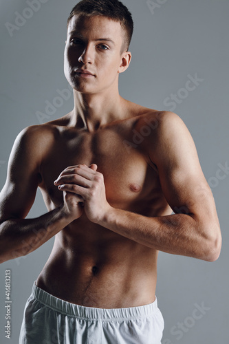 sexy athletes with inflated torso holding hands near chest on gray background 